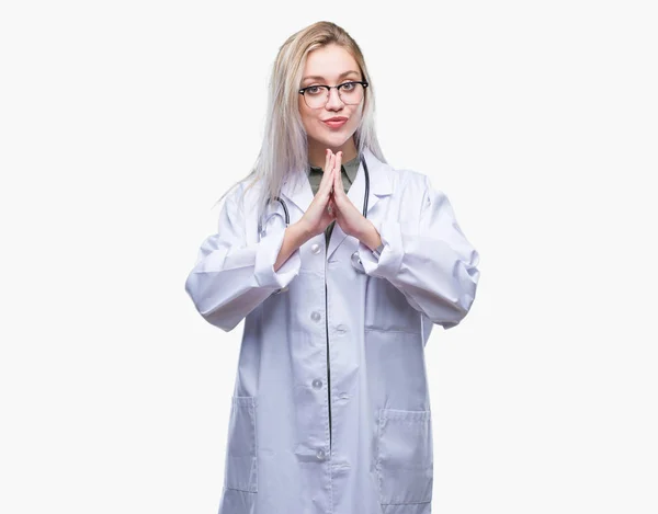 Junge Blonde Ärztin Mit Isoliertem Hintergrund Betet Mit Den Händen — Stockfoto