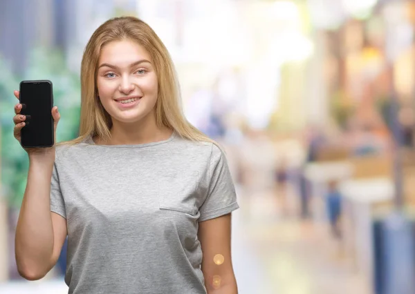 年轻的高加索妇女显示屏幕上的智能手机在孤立的背景与一个快乐的脸站着 面带微笑 自信的微笑显示牙齿 — 图库照片