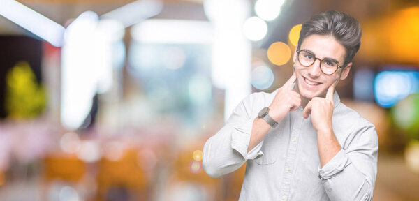 Young handsome man wearing glasses over isolated background Smiling with open mouth, fingers pointing and forcing cheerful smile