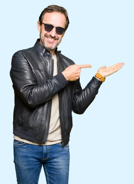 サングラスと黒い革のジャケットびっくりし 手とを提示 指で指している間カメラに笑顔を着て中年ハンサムな男 — ストック写真