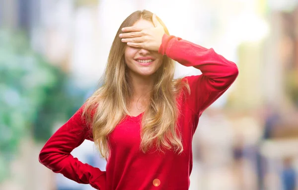 年轻美丽的金发碧眼的女人穿着红色毛衣在孤立的背景微笑和笑着用手覆盖眼睛惊喜 盲目的概念 — 图库照片