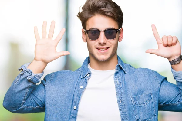 若いハンサムな男でサングラスをかけて分離を示す背景と指で上向き数は自信を持って 幸せな笑みを浮かべている間 — ストック写真