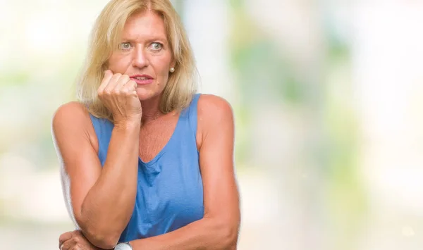 Middle age blonde woman over isolated background looking stressed and nervous with hands on mouth biting nails. Anxiety problem.