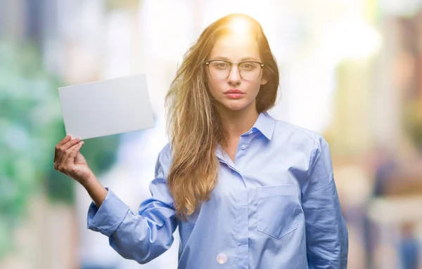 Young beautiful blonde business woman holding blank card over isolated background with a confident expression on smart face thinking serious