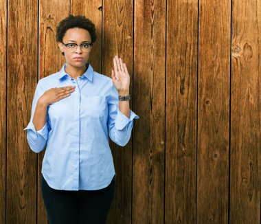 Genç güzel Afro-Amerikan iş kadını izole arka plan üzerinde göğüs ve bir sadakat sözü yemin yapma avuç, el ile küfür