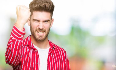 Genç yakışıklı adam giyen kırmızı gömlek öfkeli ve sinirli sinirli ve öfke ile bağırarak süre öfkeli yumruk yükselterek. Öfke ve agresif kavramı.