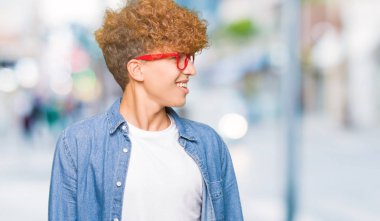 Yakışıklı genç afro saçlı gözlüklü uzak tarafına yüzünde, doğal ifade gülümseme ile seyir. Kendine güvenen gülüyor.