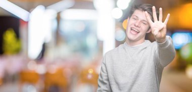 Gösterilen arka plan üzerinde sweatshirt giyen genç yakışıklı sportif adam izole ve parmakları ile işaret kendinden emin ve mutlu gülümseyerek süre dört numara.