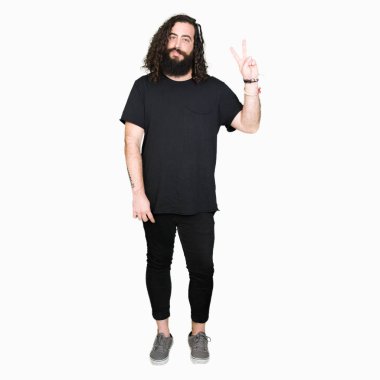 Genç adam uzun saçlı ve mutlu yüz zafer işareti yaparken kameraya göz kırpıyor ile gülümseyen giyen heavy metal siyah kıyafeti sakal. İki numaralı.