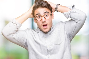 Üzerinde gözlük takan genç yakışıklı adam arka plan deli izole ve baş, korkuyor ve açık ağzı ile şok sürpriz elleriyle korkuttu