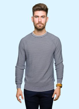 Yüzünde çizgili süveter gevşek ciddi ifade ile giyen genç yakışıklı adam. Basit ve doğal kameraya bakıyor.