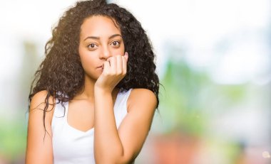 Stresli ve gergin ile eller tırnak ısırma dudaklarından seyir kıvırcık saçlı Genç güzel kız. Anksiyete sorunu.