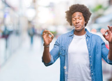 İzole arka plan üzerinde Afro Amerikalı adam rahatla ve gülümseyen gözlerle kapalı parmak jestle meditasyon yapıyor. Yoga kavramı.