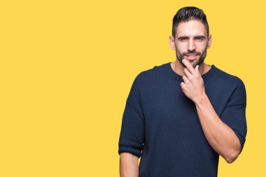 Emin çapraz kollar ve çeneme kaldırdı el ile gülümseme ile kameraya bakarak izole arka plan üzerinde kazak giyen genç yakışıklı adam. Pozitif düşünce.