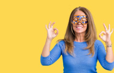 Güzel orta yaş kadın giyiyor Venedik Karnavalı maskeyi izole arka plan üzerine dinlenmek ve gülümseyen gözlerle kapalı parmak jestle meditasyon yapıyor. Yoga kavramı.