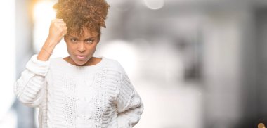 Üzerinde kış kazak giyen güzel genç Afro-Amerikan kadın arka plan kızgın izole ve kızgın yetiştirme hayal kırıklığı ve öfke ile bağırarak süre öfkeli yumruk. Öfke ve agresif kavramı.