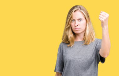 Öfkeli ve sinirli sinirli ve öfke ile bağırarak süre öfkeli yumruk yükselterek izole arka plan üzerinde büyük boy rahat t-shirt giyen güzel ve genç birbayan. Öfke ve agresif kavramı.