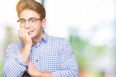 Genç yakışıklı adam stresli ve gergin ile izole arka plan üzerinde gözlük takan tırnak ısırma dudaklarından eller. Anksiyete sorunu.