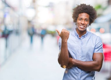 Seyir ve başparmak yanında yukarıyı mutlu yüz ile gülümseyen izole arka plan üzerinde Afro Amerikalı adam.