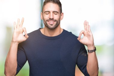 Genç yakışıklı adam giyen kazak izole arka plan üzerinde dinlenmek ve gülümseyen gözlerle parmak ile meditasyon jest yapıyor kapalı. Yoga kavramı.
