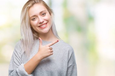 Sarışın genç kadın izole arka neşeli bir gülümseme ile el ve parmak kadar kameraya bakarak yüzündeki mutlu ve doğal ifade ile yan ile işaret yüz üzerinden.