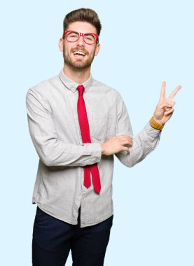 Mutlu yüz zafer işareti yaparken kameraya göz kırpıyor ile gülümseyen gözlüklü genç yakışıklı iş adamı. İki numaralı.