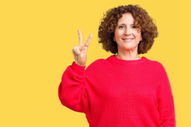 Güzel orta ager üst düzey kadın kırmızı kış kazak üzerinde gösterilen arka plan izole ve parmakları ile işaret kendinden emin ve mutlu gülümseyerek ise ikinci.