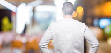 İzole arka plan ayakta geriye doğru uzakta silah ile vücut üzerinde seyir üzerinde sweatshirt giyen genç yakışıklı adam