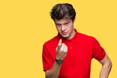 Beckoning gel burada mutlu ve gülümseyerek el davet ile jest izole arka plan üzerinde kırmızı t-shirt giyen genç yakışıklı adam