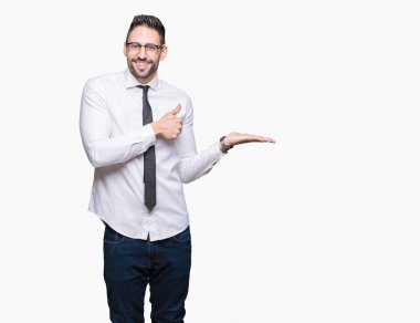 Üzerinde gözlük takan genç yakışıklı iş adamı arka plan gösteren palm el ve iş tamam jestle başparmak yukarıya, mutlu ve neşeli gülümseyen izole