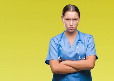İzole arka plan şüpheci ve sinir, onaylamayan ifade yüz çapraz kolları üzerinde tıbbi üniforma giyen genç beyaz doktor kadın. Negatif kişi.