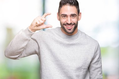 Yakışıklı genç gülümseyen izole arka plan ve süre seyir ve kamera boyutu işaret parmaklarıyla yapıyor el ile kendinden emin eller üzerinde kazak giyiyor. Ölçü kavramı.