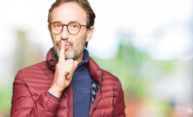 Gözlük ve dudaklarında parmak ile sessiz olmanı kış ceket giyen orta yaş yakışıklı adam. Sessizlik ve gizli kavramı.