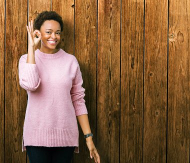 Gülümseyen izole arka plan üzerinde güzel genç Afro-Amerikan kadın el ve parmaklar ok işaretiyle yapıyor olumlu. Başarılı ifade.