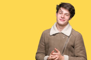 Arka plan eller üzerinde kış ceket giyen genç yakışıklı adam birlikte izole ve rahat ve neşeli gülümseyen parmak çarpı işareti. Başarı ve iyimser