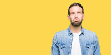 Komik surat ile yanakları şişirme denim ceket giyen sakal ve mavi gözlü yakışıklı adam. Ağız ile hava, deli ifade şişirilmiş.