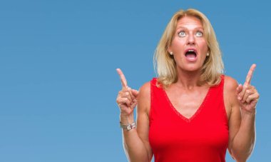 Orta yaş sarışın kadın izole arka plan üzerinden hayran ve yukarıya bakıp parmakları ile işaret şaşırttı ve silah kaldırdı.