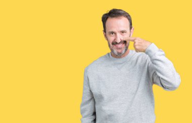 Yakışıklı orta yaş komuta sizde bir kazak izole üzerinde giyen arka plan işaretçi el parmak yüz ve burun, neşeli gülümseyen