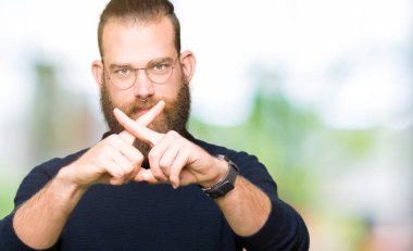 Genç sarışın adam gözlük ve balıkçı yaka kazak ret ifade geçiş parmakları eksi işareti yapıyor