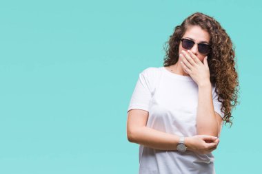 Güzel esmer kıvırcık saçlı Genç kız üzerinde güneş gözlüğü takıyor arka plan ağız hata için elleriyle kapsayan şok izole. Gizli kavramı.