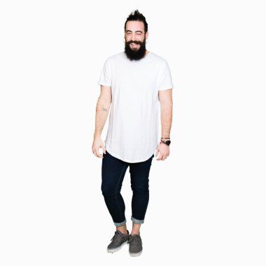 Uzun saç ve sakal casual beyaz t-shirt seksi bir ifadeyle, neşeli ve mutlu yüzünü kameraya bakarak göz kırpıyor giyen genç hipster adamla.