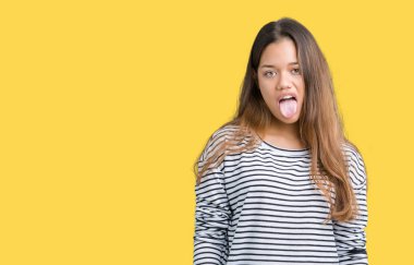 Giyen genç güzel esmer kadın çizgili süveter dilini izole arka plan üzerinde out komik ifade ile mutlu. Duygu kavramı.