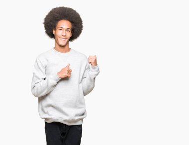 Sportif sweatshirt giyen afro saçlı genç Afro-Amerikan adam kendinden emin gülümseyen arkasından el ve kadar başparmak ile işaret