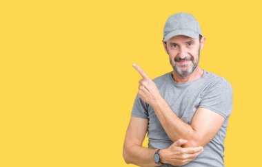 Yakışıklı orta yaş ağarmış kıdemli adam giyiyor spor kap üzerinde izole reklam, ciddi ve sakin yüz gösterilen yan el parmak ile işaret arka plan