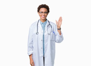 İzole arka plan Waiving mutlu selam söyleyerek üzerinde tıbbi ceket ve gülümseyen, dostça karşılama jest giyen genç Afro-Amerikan doktor kadın