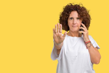 Orta ager üst düzey kadın Smartphone'da açık eliyle dur işareti ile ciddi ve kendine güvenen ifade, savunma jest yapıyor izole arka plan üzerinde söz