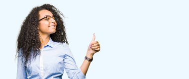 Yanına bir jest yapıyorsun gülümseyen genç güzel iş kız kıvırcık saçlı gözlüklü gurur, seyir yaşasın