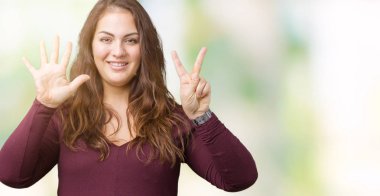 Parmakları ile yedi gülümseyen ise kendinden emin ve mutlu güzel ve çekici artı boyutu genç kadın ve yukarıyı gösteren izole arka plan üzerinde elbise numaralı.
