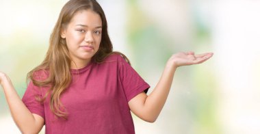 Genç güzel esmer kadın izole arka plan clueless ve şaşkın bir ifadeyle kollar ve eller kaldırdı. Şüphe kavramı.