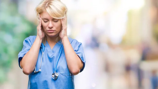 Young beautiful blonde doctor woman wearing medical uniform over isolated background with hand on head for pain in head because stress. Suffering migraine.